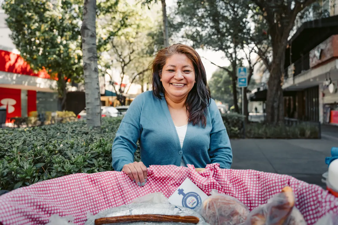 Una vendedora sonríe detrás de su carrito de churros en una calle de Ciudad de México.